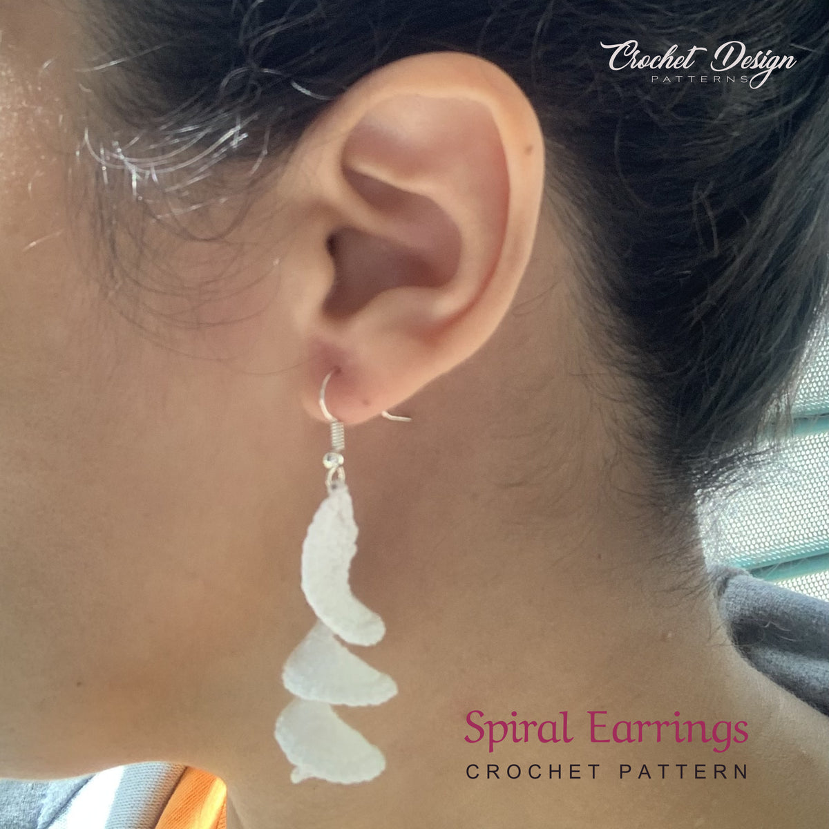 Crochet spiral earrings worn by model, close-up on ear