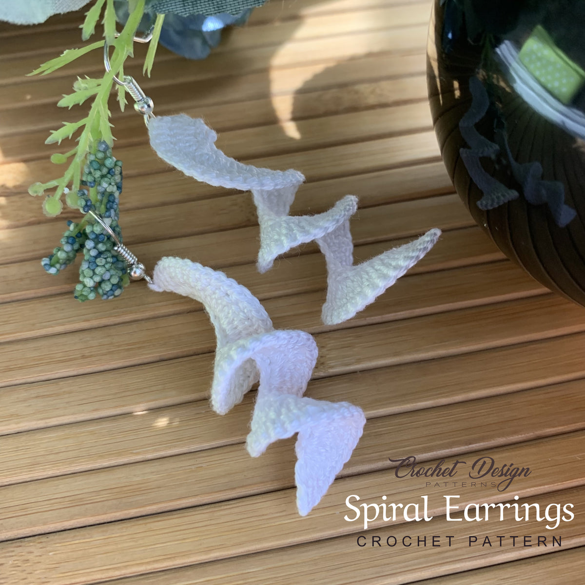 White crochet spiral earrings laid flat on wooden surface